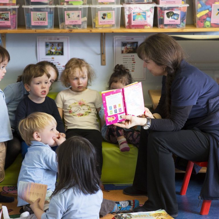 children reading a book with the teacher