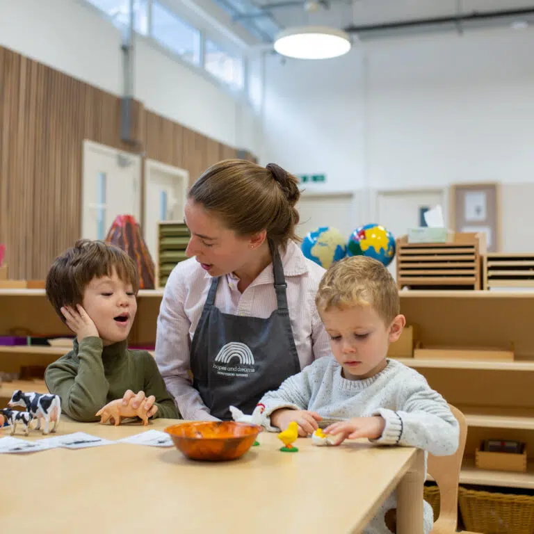 2 kids learning with a teacher looking on